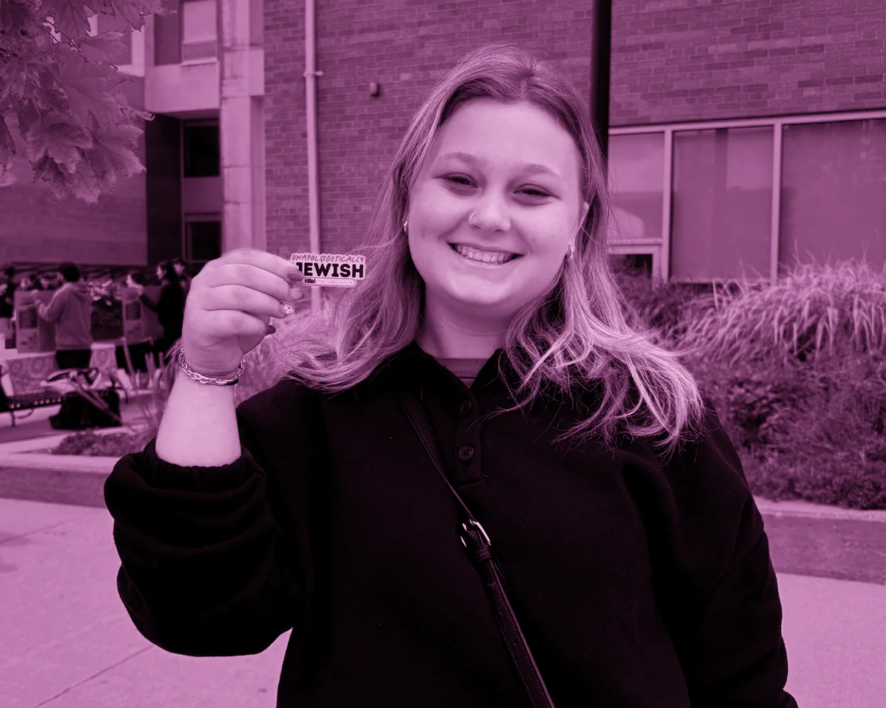 Rebekah holding an Unapologetically Jewish sticker on campus